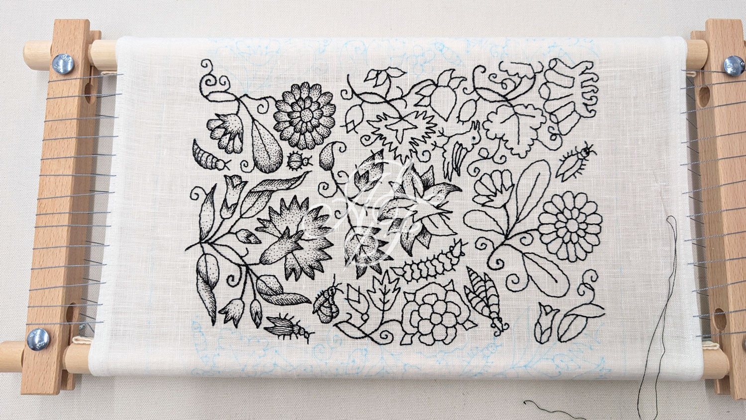 Early 1600s century blackwork coif embroidery in progress on a rotating slate frame, with Holbien stitch outlines and seed stitch shading