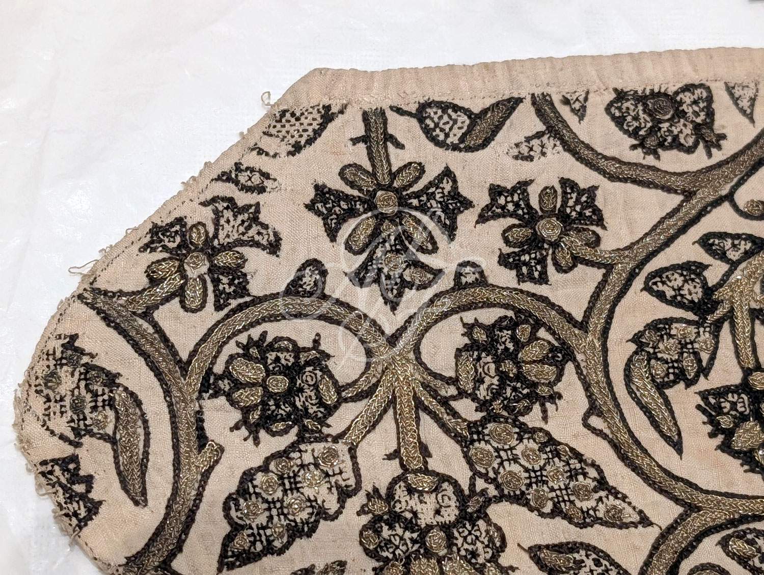 Late 16th century linen coif with blackwork embroidery in geometric fill patterns and silver gilt plaited trim