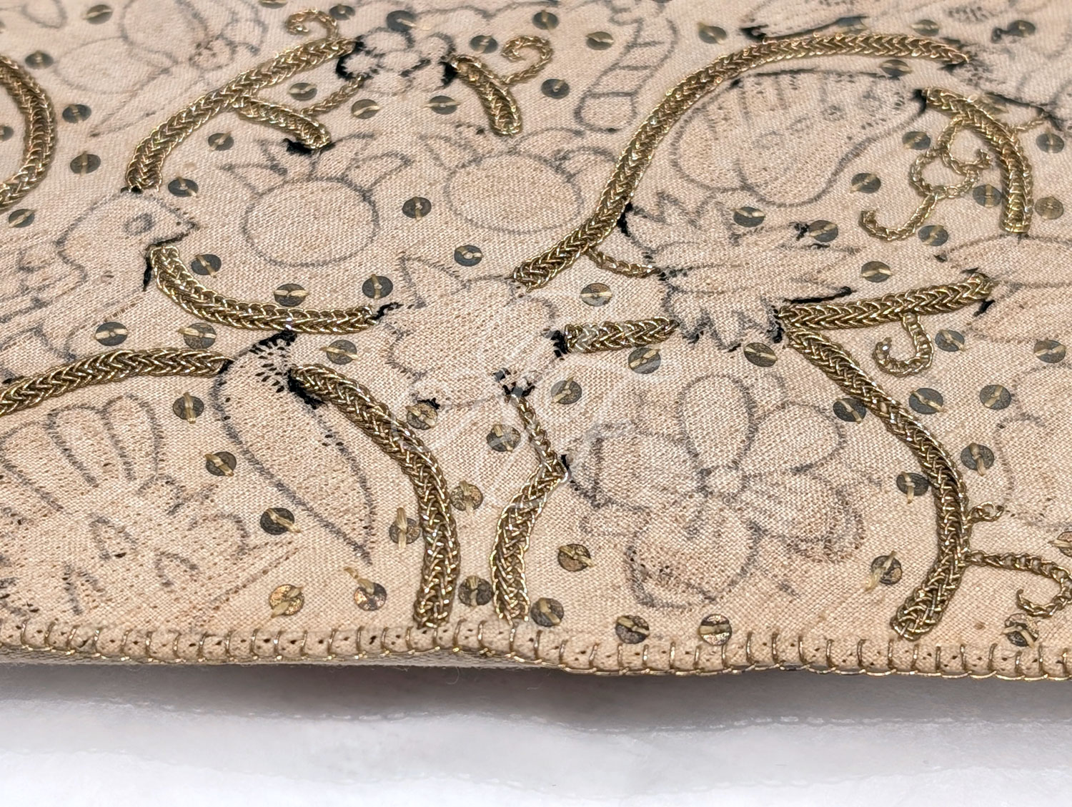 Closeup of embroidery and silver gilt braid on a Jacobean coif and forehead cloth set at the V&A