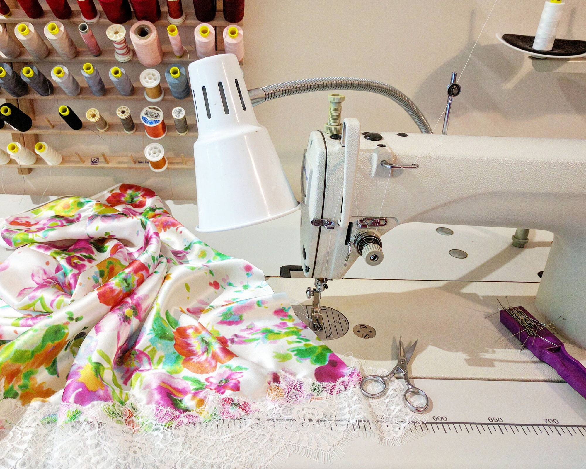 Angela Friedman working at a sewing machine on a silk slip in her studio